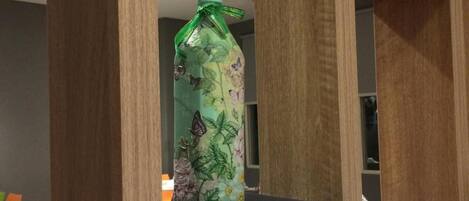 A bottle with a floral design on a white shelf in a modern room with wooden accents.