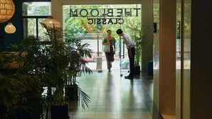 Un pasillo con plantas en macetas, un letrero que dice "MOONLIGHT CAFE" y una persona agachándose.