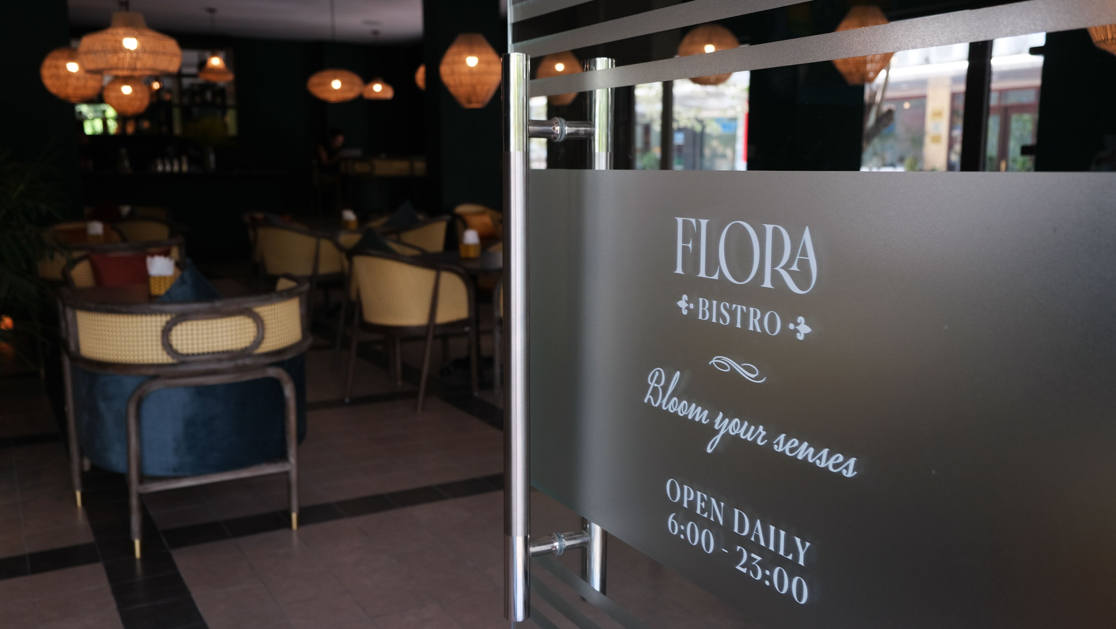A restaurant interior with a sign reading "FLORA + BISTRO" and "Bloom your senses" indicating a dining area.