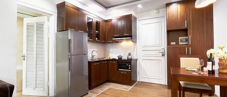A compact kitchen with wooden cabinets, a stainless steel refrigerator, and a microwave.