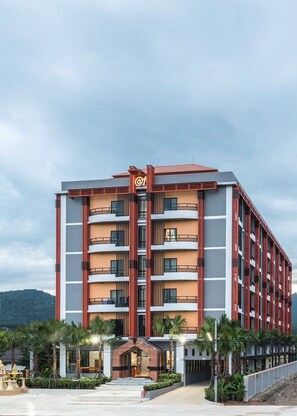 A modern hotel with a central entrance, multiple balconies, and a prominent logo.