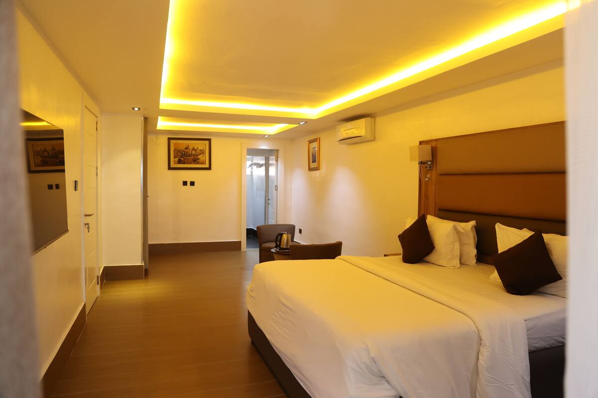 A hotel room with a large bed, a chair, a small table, and a picture on the wall.