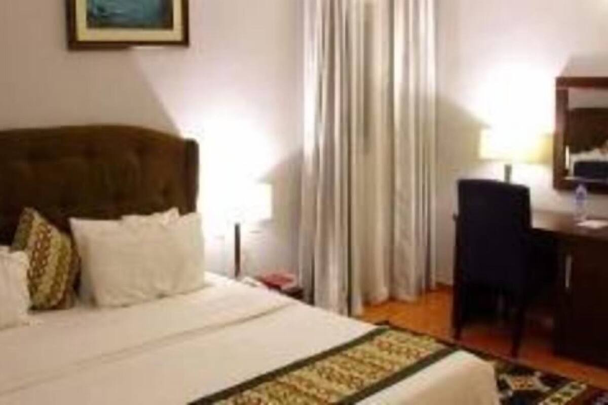 A hotel room with a bed, a desk, and a chair.
