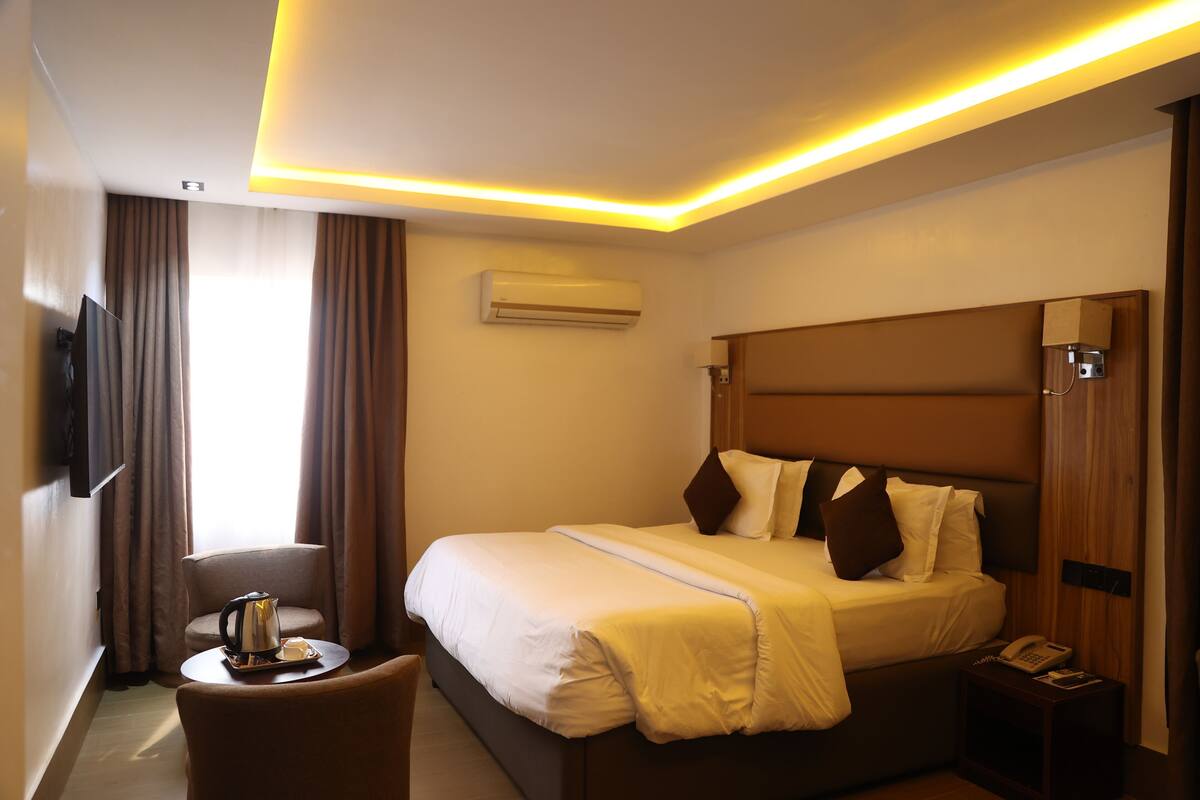 A hotel room with a bed, bedside table, and a television.