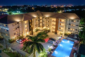 A multi-story hotel with a swimming pool and outdoor seating area.