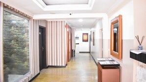 A hotel corridor with a reception desk, a large glass door, and a wall-mounted mirror. - Béni Apartments (Lagos)