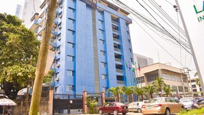 A multi-story building with balconies, a gated entrance, and parked cars. - Béni Apartments (Lagos)