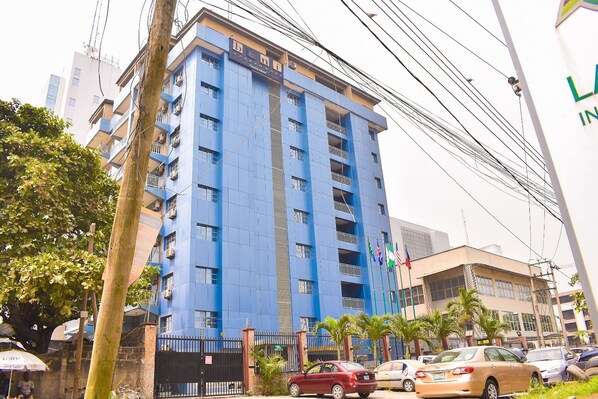 A multi-story building with balconies, a gated entrance, and parked cars. - Béni Apartments (Lagos)