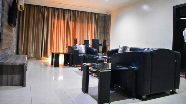A modern living room with a sofa set, a coffee table, and a flat-screen TV mounted on the wall. - Béni Apartments (Lagos)