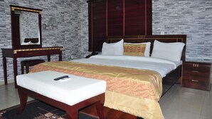 A bedroom with a bed, bedside table, mirror, and wardrobe. - Béni Apartments (Lagos)
