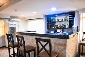 A bar area with a stone counter, bar stools, and a variety of liquor bottles. - Béni Apartments (Lagos)