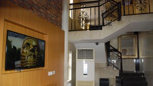 Eine Treppe mit schwarzer Metallreling, einer Wandklimaanlage und einem gerahmten Bild an der Wand.