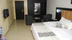 Ein Hotelzimmer mit einem Bett, einem Schreibtisch, zwei Stühlen, einem Fernseher und einem Wasserspender.