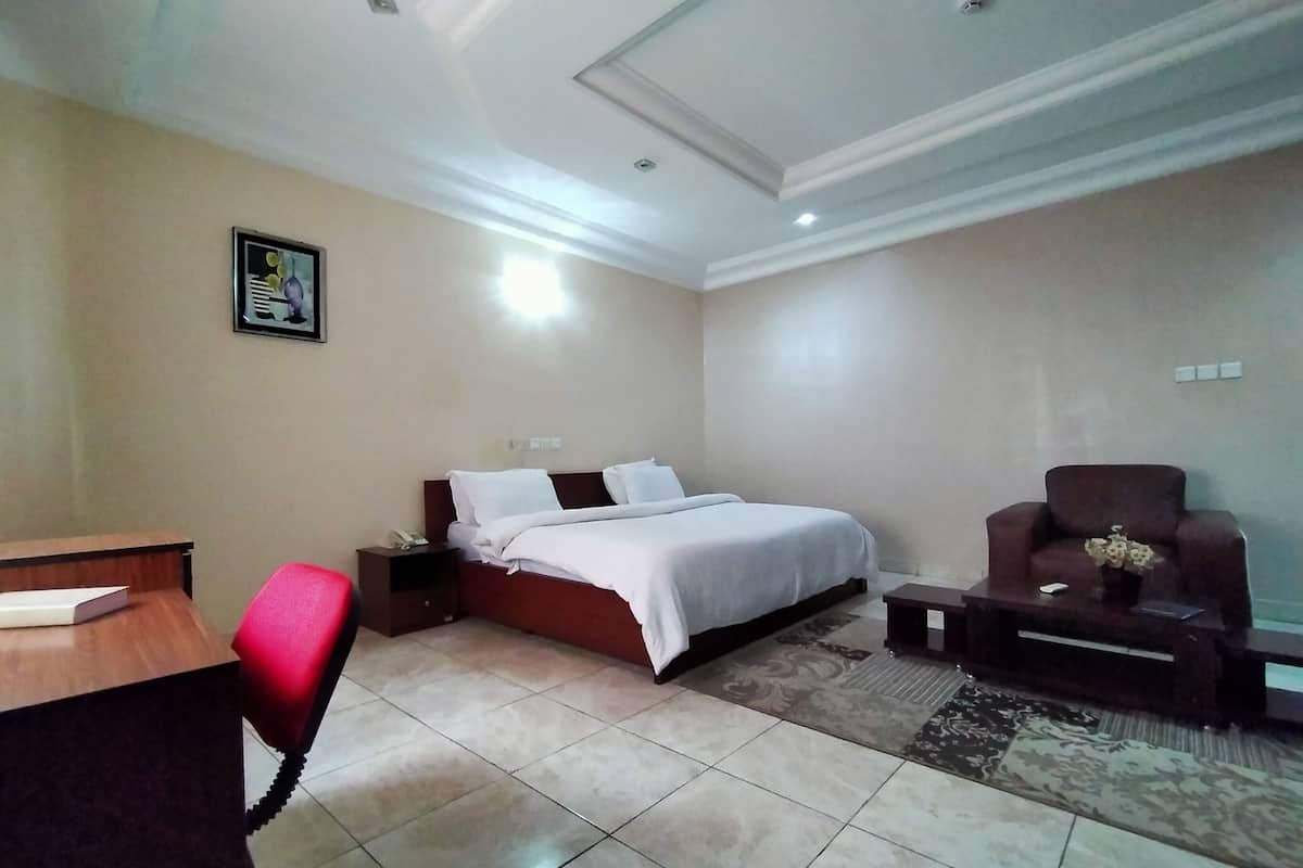 Una habitación de hotel con una cama, un escritorio, una silla y una mesita con un florero.