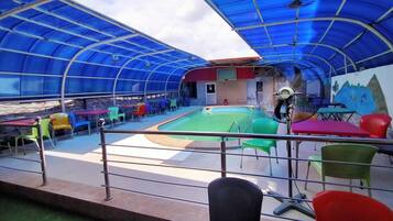 A covered outdoor area with a pool, seating, and a fan.