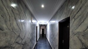 A corridor with marble walls and a dark floor, leading to a door marked with the number 315. - Laps New World Hotel (Abuja)
