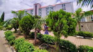 A hotel with a modern design, featuring a large building with multiple windows and a red roof. - Laps New World Hotel (Abuja)