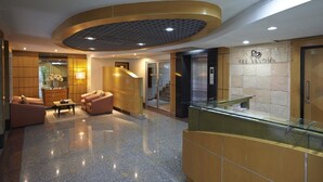 Een moderne lobby met een gebogen plafond, een receptiebalie en een trap naar een lift.