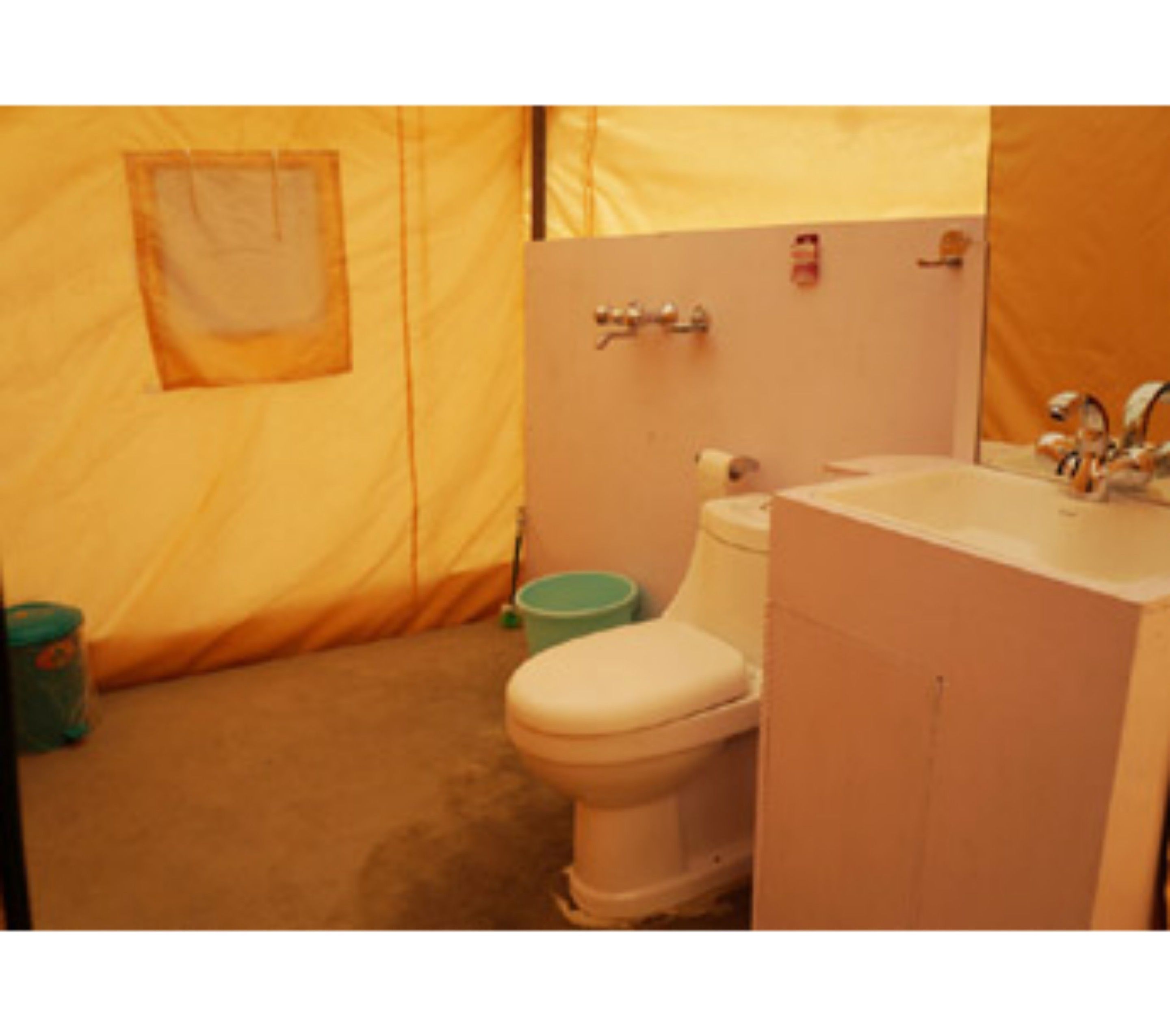 Et lille badeværelse med toilet, håndvask og skraldespand.