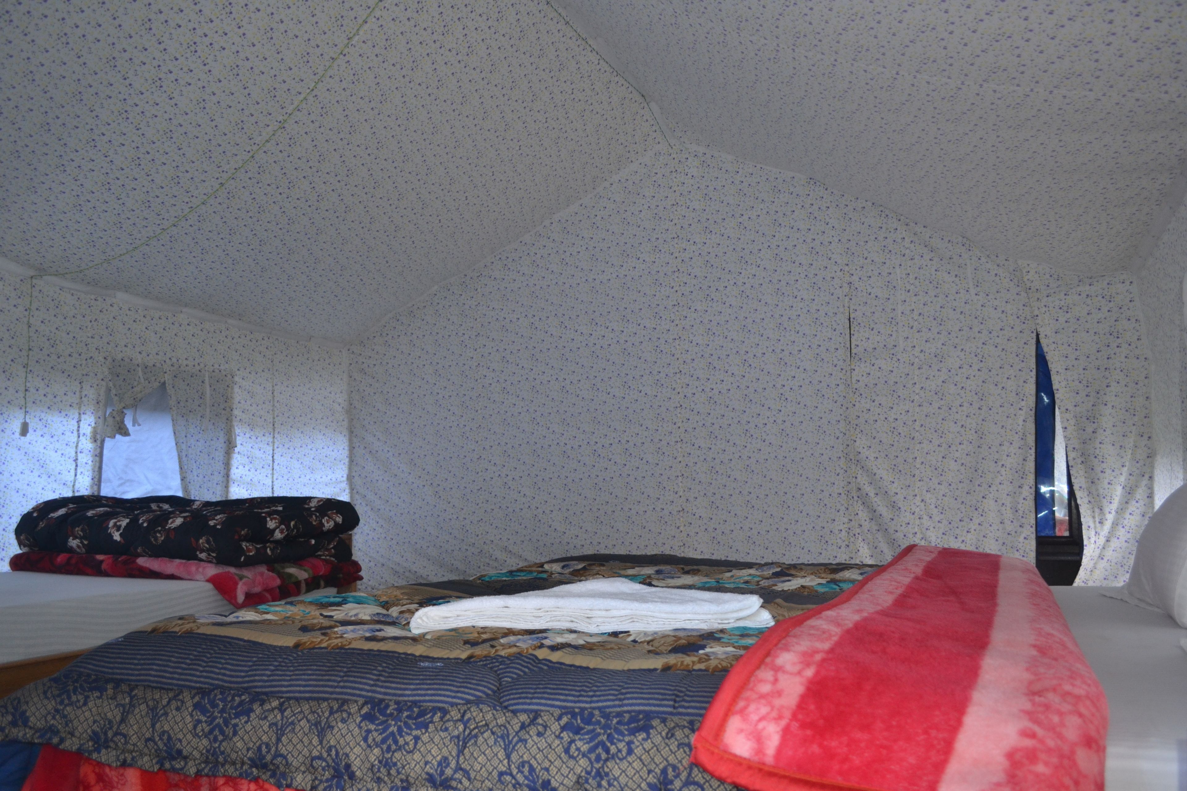 A tented room with a bed, blankets, and pillows.