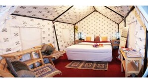 A tent-style room with a bed, a wooden chair, a small table, and a nightstand. - Nubra Summer Camp (Leh)