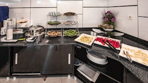 A buffet setup with various food items and condiments on a black countertop. - Madi Otel Izmir (Izmir)