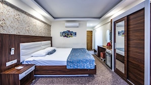 A modern hotel room with a large bed, a bedside table, a wardrobe, a mirror, and a wall-mounted air conditioner. - Madi Otel Izmir (Izmir)