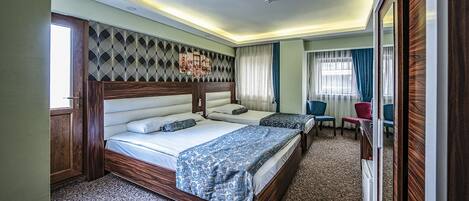 A hotel room with two beds, a large mirror, a wooden headboard, and a carpeted floor.
