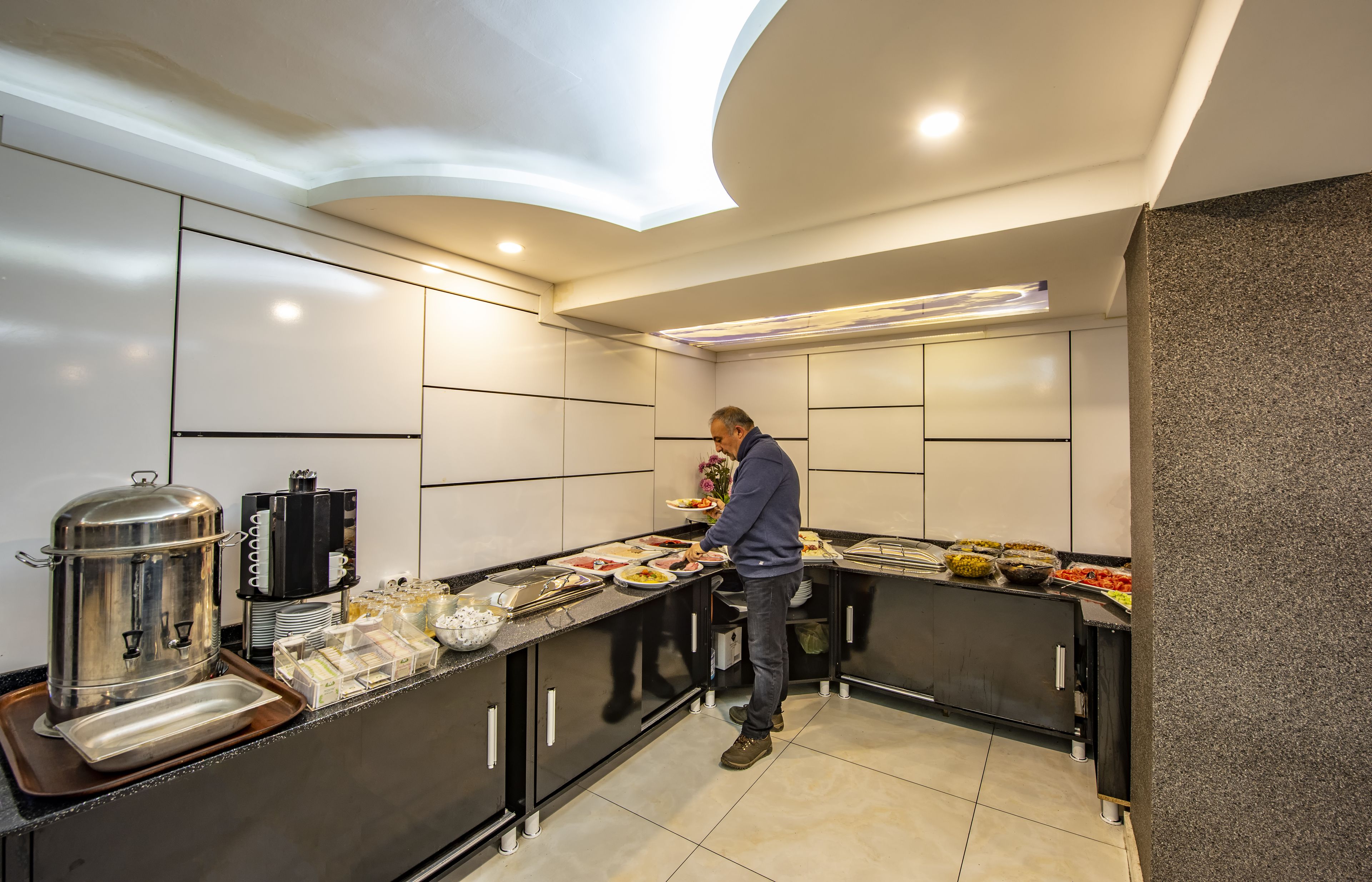 A modern kitchen with a buffet setup, including a coffee machine and various food items.