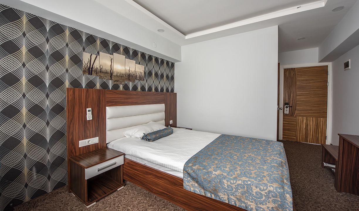 Un dormitorio con estructura de cama de madera, una mesita de noche y una pared con estampado.