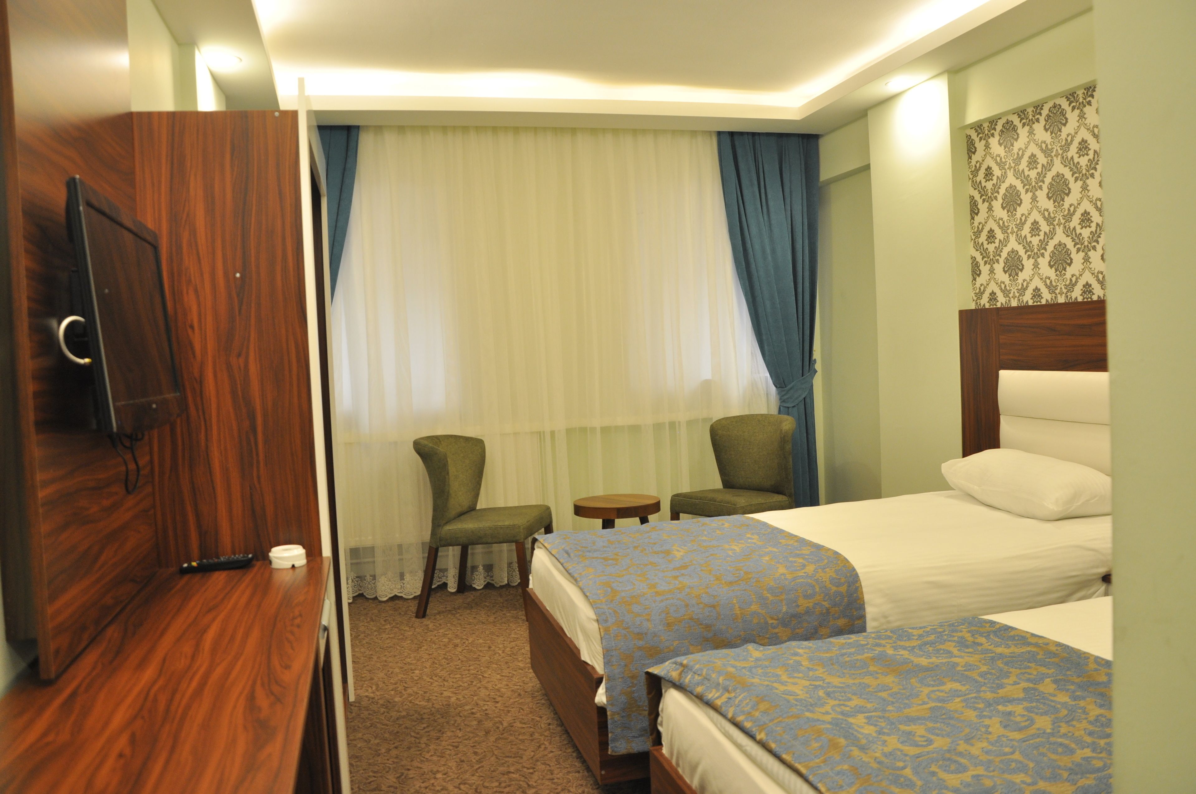 A hotel room with two beds, a TV, a small table, and a chair.