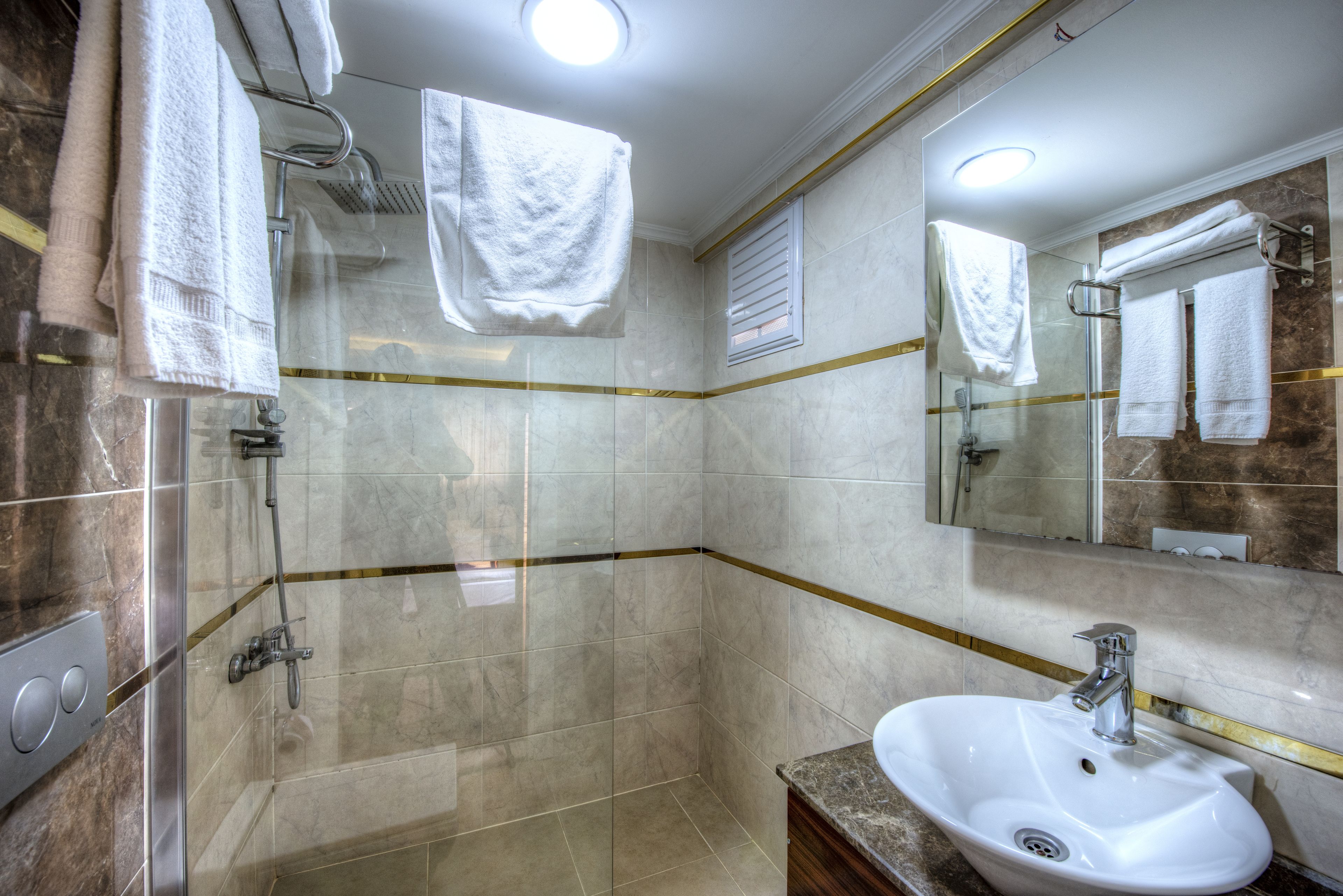 Ein modernes Badezimmer mit einer gläsernen Dusche, einem weißen Waschbecken und einem großen Spiegel.