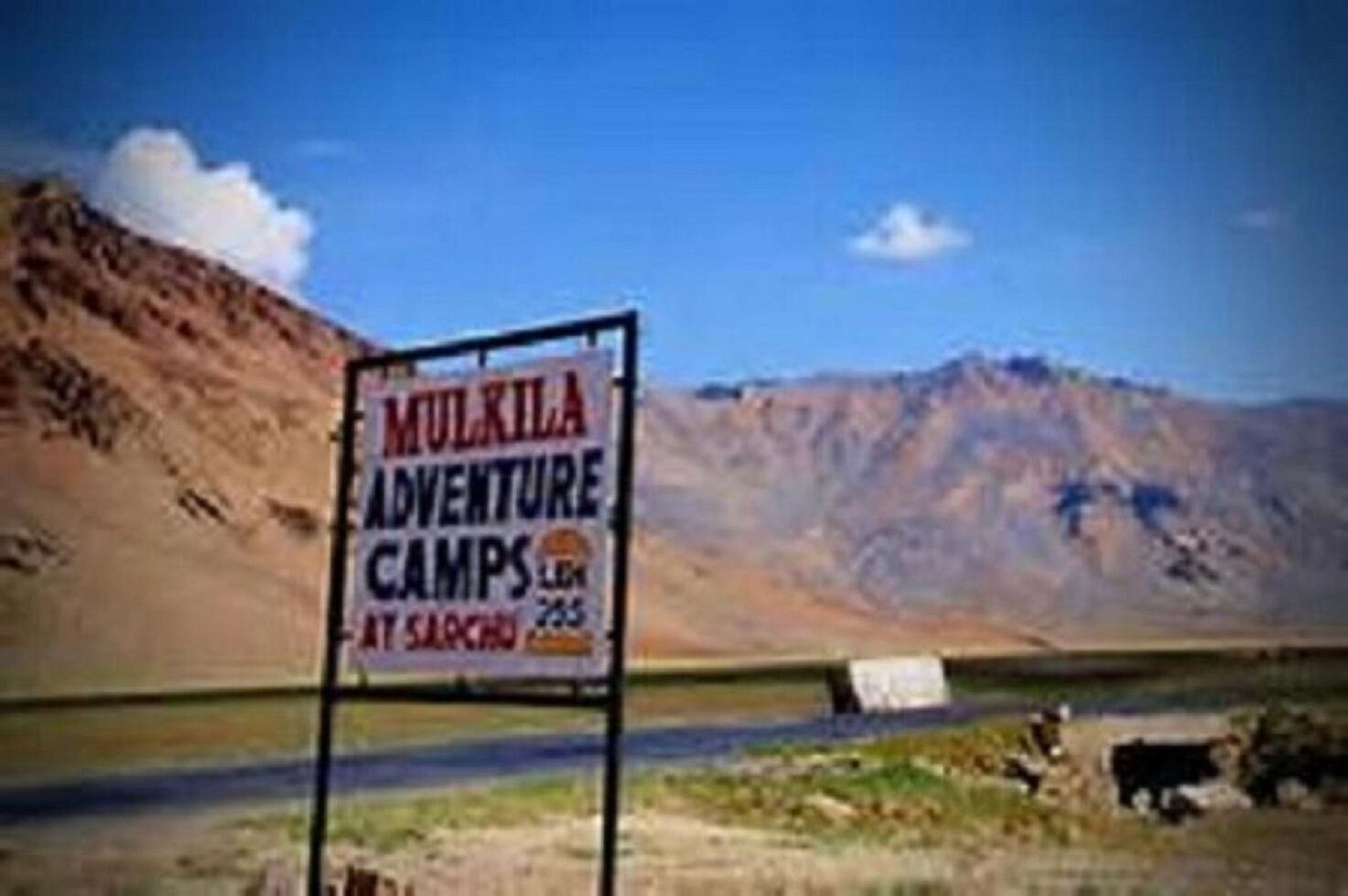 A sign for Mulkila Adventure Camps with a mountainous backdrop.