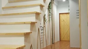 A staircase with wooden steps and handrails, leading to a door at the end of a hallway with wooden flooring. - Barn and Bed Hostel (Bangkok)