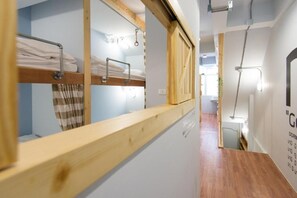 A dormitory room with bunk beds, a wooden headboard, a towel rack, and a mirror. - Barn and Bed Hostel (Bangkok)
