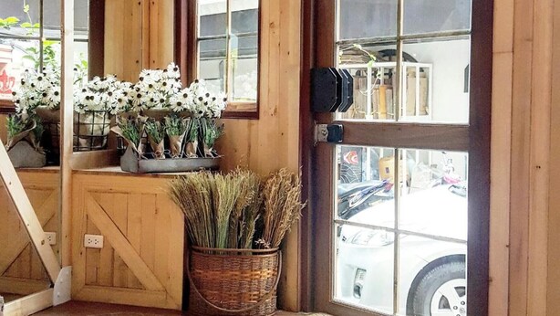 A wooden interior with large windows, a door with a handle, and a basket of dried plants. - Barn and Bed Hostel (Bangkok)
