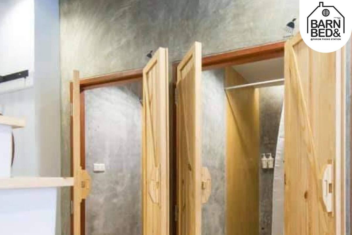 A bathroom with wooden doors, a shower area, and a white countertop.