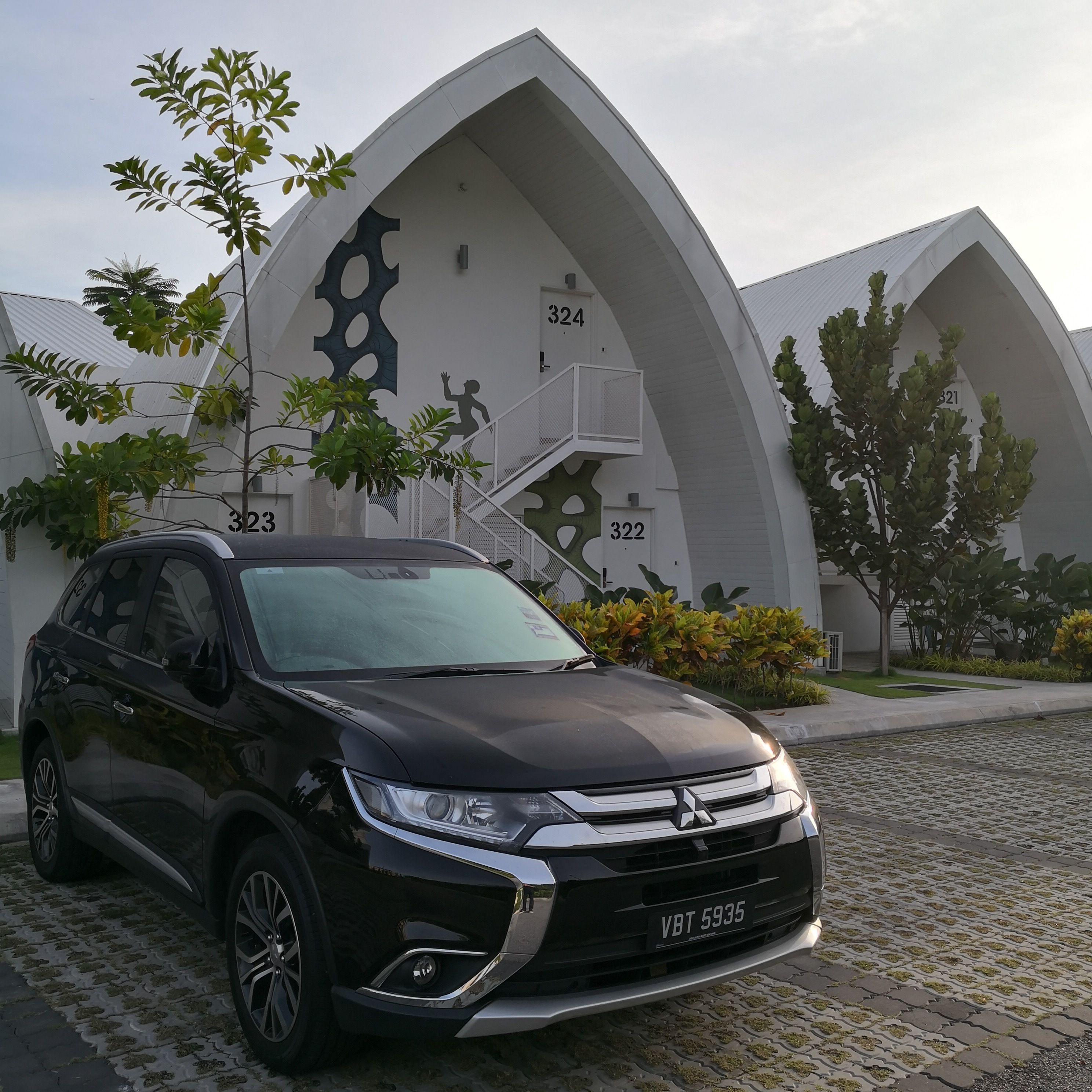 A black SUV parked in front of a modern building with unique architectural design, including numbered sections and a staircase.