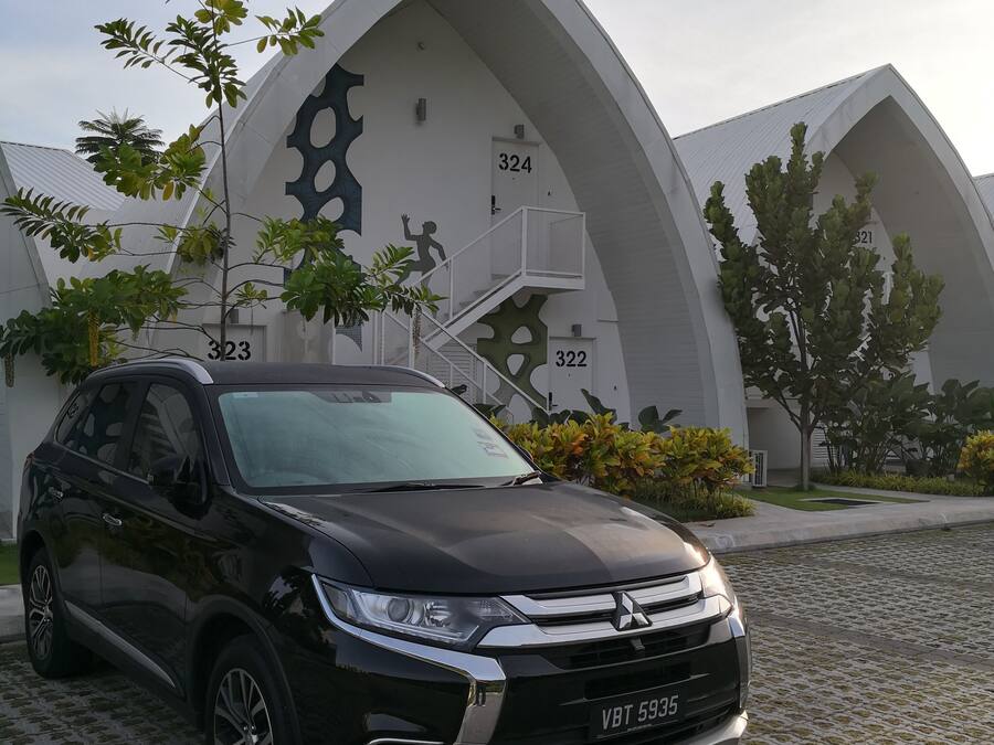 A black SUV parked in front of a modern building with unique architectural design, including numbered sections and a staircase.