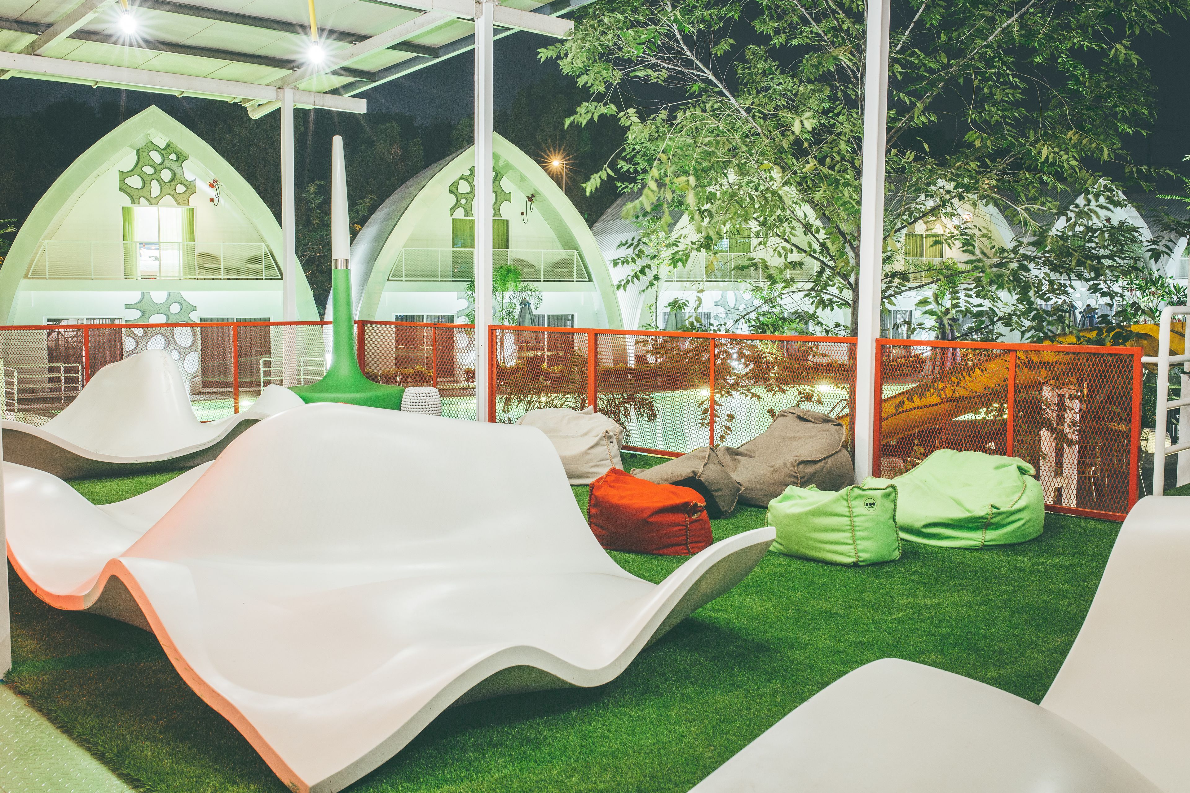 Un parque infantil con toboganes y sillones de mimbre sobre césped artificial.
