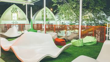 Un parque infantil con toboganes y sillones de mimbre sobre césped artificial.