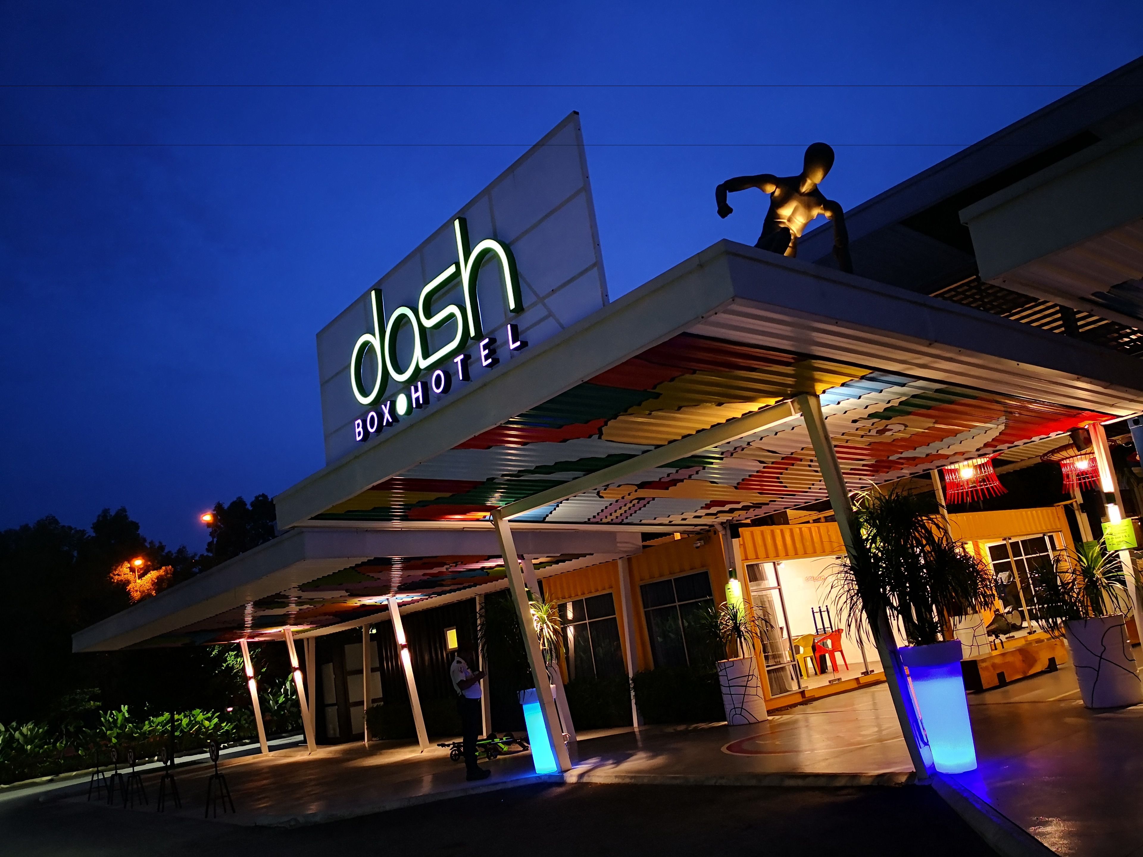 A hotel entrance with a large illuminated sign, a covered outdoor area, and a statue.