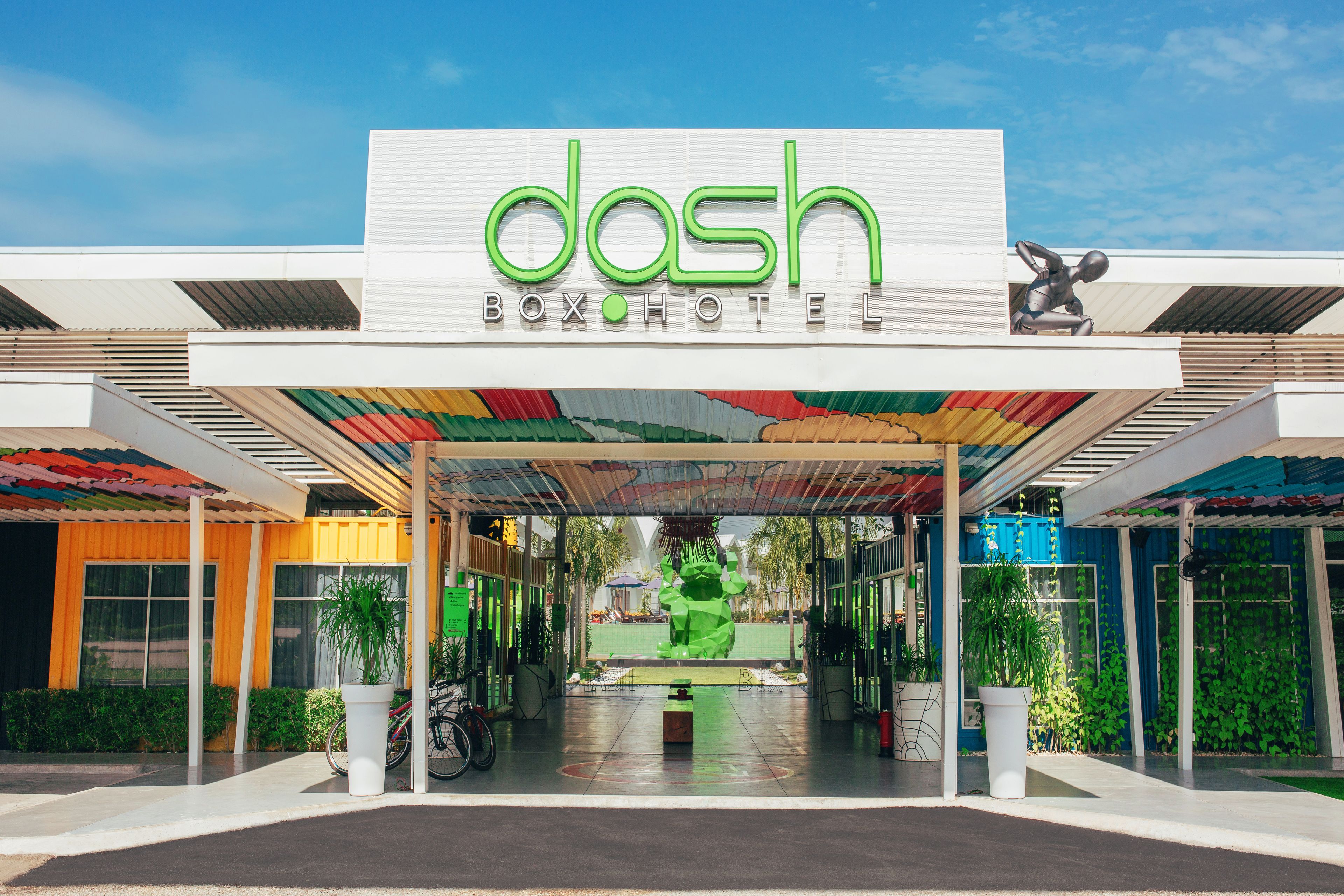 L’entrée de l’hôtel Dash Box, avec son toit aux couleurs vives et une grande sculpture verte au centre.