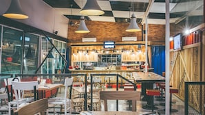 A restaurant with a brick wall, hanging pendant lights, and a bar area. - Dash Box Hotel Cyberjaya (Cyberjaya)