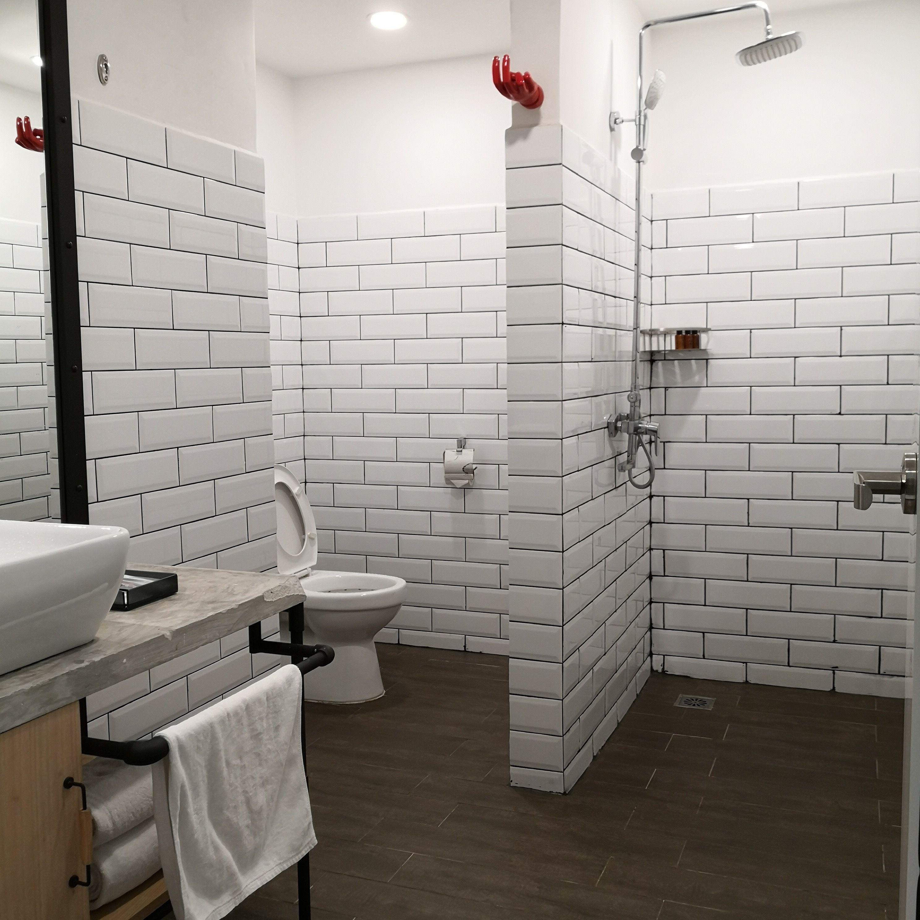 Un baño moderno con azulejos blancos tipo metro, inodoro, lavamanos y ducha.