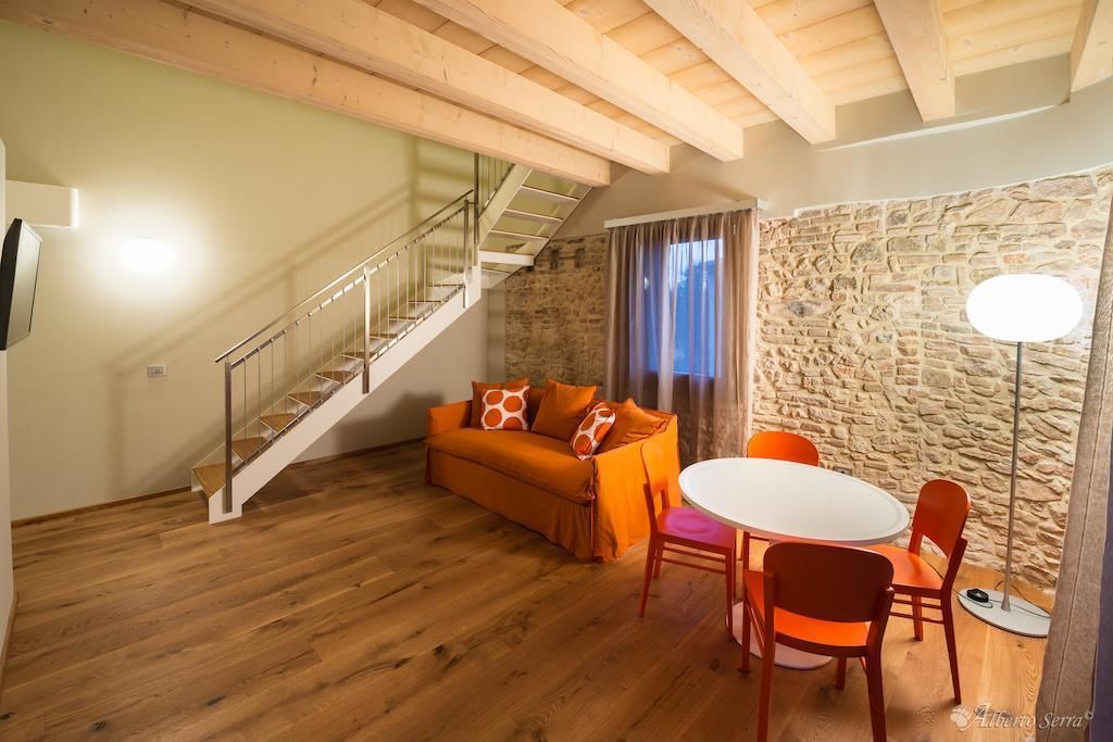 A cozy living area with a wooden staircase, a stone wall, and a sofa with orange cushions.