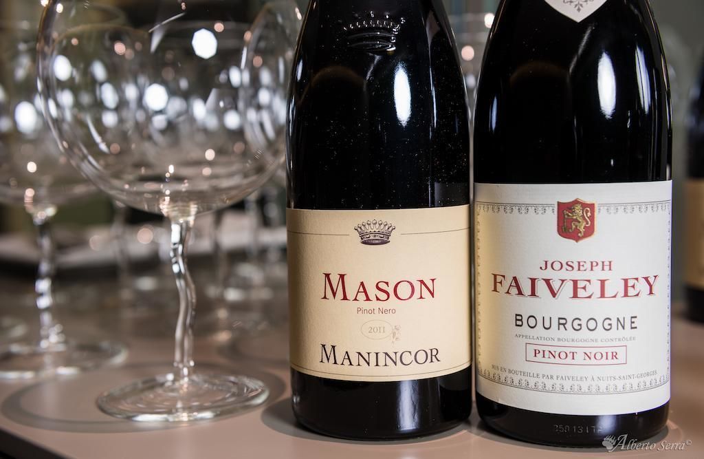 Two wine bottles, one labeled 'MASON' and the other 'JOSEPH FAIVELEY BOURGOGNE PINOT NOIR', with wine glasses in the background.