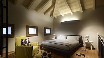 A bedroom with a bed, a chair, a nightstand, and a lamp.