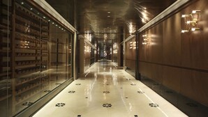 A modern hotel corridor with a reflective floor, glass display cases, and warm lighting. - The Lotus Hotel Chongqing (Chongqing)