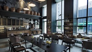 A modern interior with a long dining table, comfortable seating, a kitchen area, and large windows offering views of the city. - The Lotus Hotel Chongqing (Chongqing)